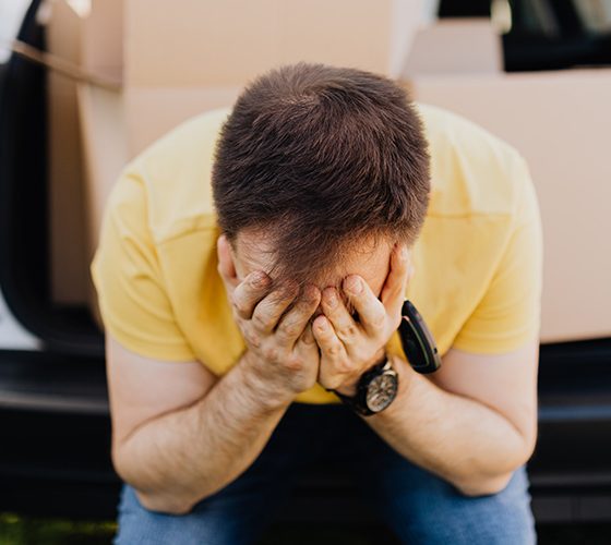Man seated in trunk of car, head in hands as he feels homebuying regret. Avoid these with your clients.