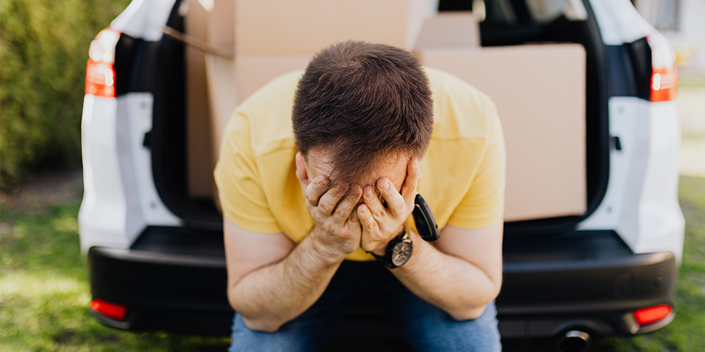 Man seated in trunk of car, head in hands as he feels homebuying regret. Avoid these with your clients.