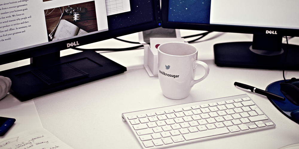 A desk with a blogging website open on the computer and coffee cup in front.