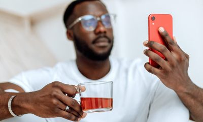 Man holding cup and phone representing possible addiction.