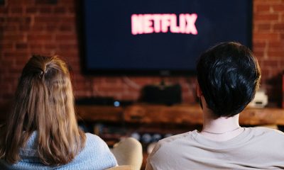 Two people watching Netflix on a TV while seated on a couch.