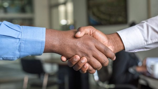 Two sales people shaking hands representing being a leader