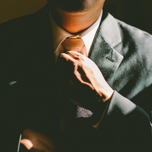 Man in suit fixing tie representing being successful