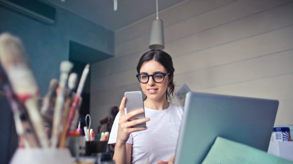 Person looking at phone with clutter on desk, not representing a clean work space.
