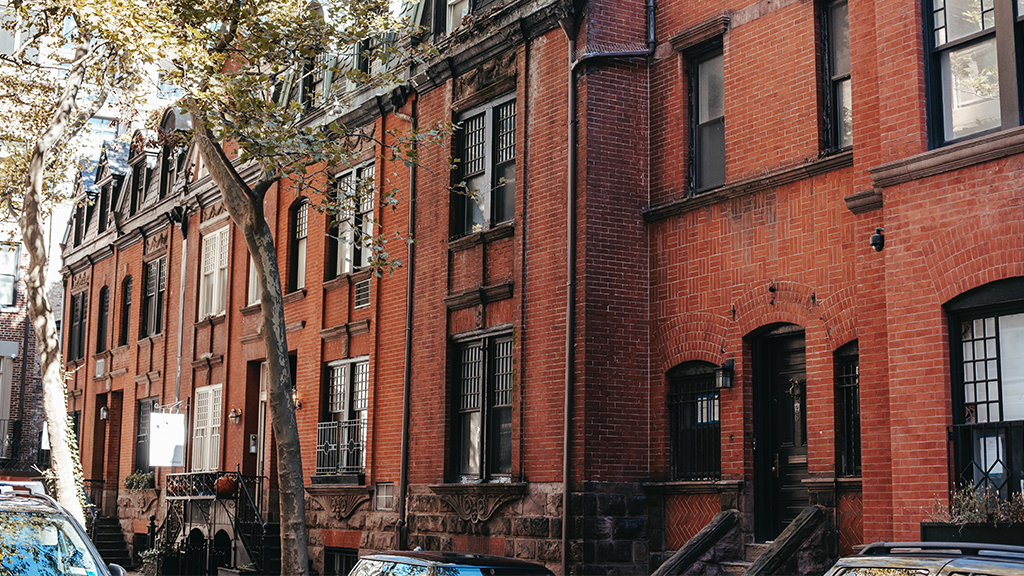A neighborhood of brick walled apartments and townhomes, with a view from the sidewalk.