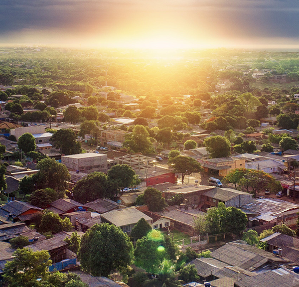 An aerial view of a neighborhood with the sun rising just beyond the swath of houses with lower interest rates.