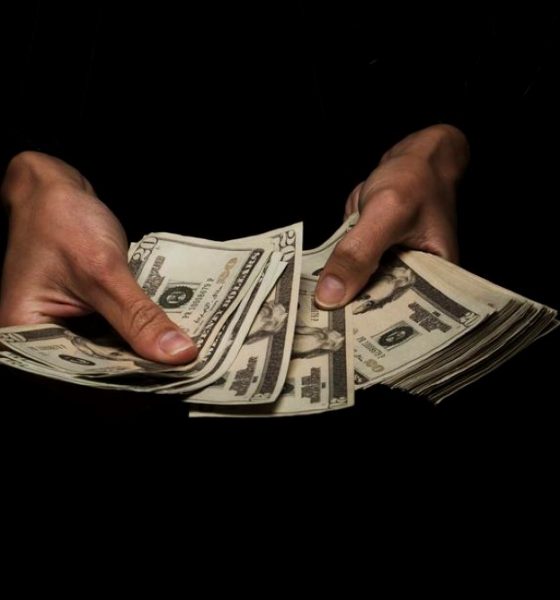 Man holding money in the dark representing false salary transparency.