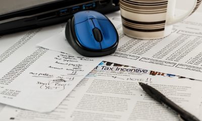Tax return paperwork with blue computer mouse, pen, and coffee mug.