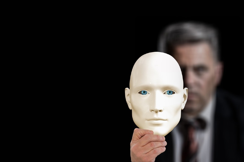 Man holding mask representing imposter syndrome.