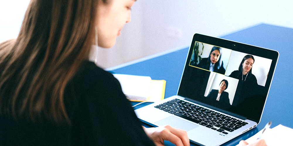 Woman networking through Zoom video call with two other women.