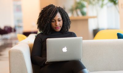 Black woman working on a laptop on a couch, running her small businesses' needs digitally.