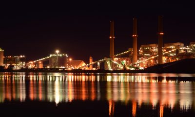 Manufacturing plant at night across the water with orange and red reflections.