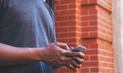 Man texting chatbots leaning against a brick wall.