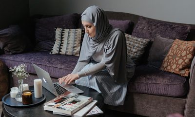 Woman in hijab sitting on couch, working from home on a laptop