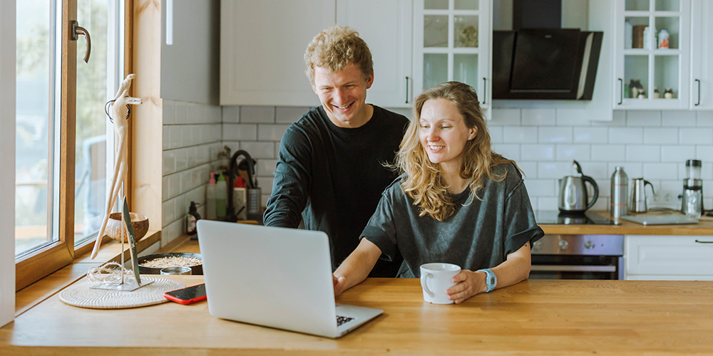 Man and woman at kitchen table online shopping on laptop together, boosting customer loyalty.