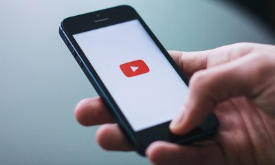YouTube Premieres app opening on a smartphone being held in a hand.