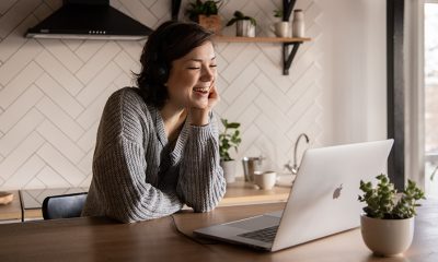 A woman in kitchen with laptop smiling at the screen during a Google Meet video meeting.