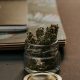 A small jar of cannabis on a desk with notebooks, sold online in a nicely made jar.