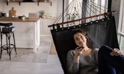 Woman in a hammock in a kitchen, talking on the phone using Clubhouse app.