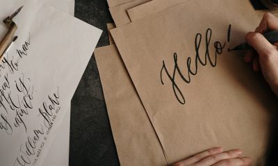 Small business owner drawing calligraphy "Hello!" on brown paper sourced from Paper Source.