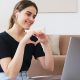 Woman forming hands into heart shape at laptop hosting live video chat, similar to Facebook's new app Hotline