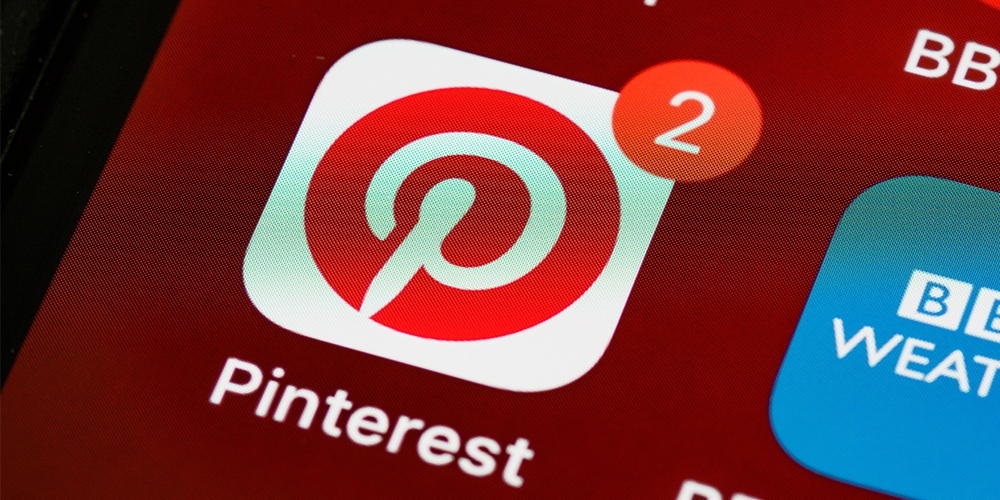 Pinterest icon on phone with 2 notifications, indicating new code of conduct.
