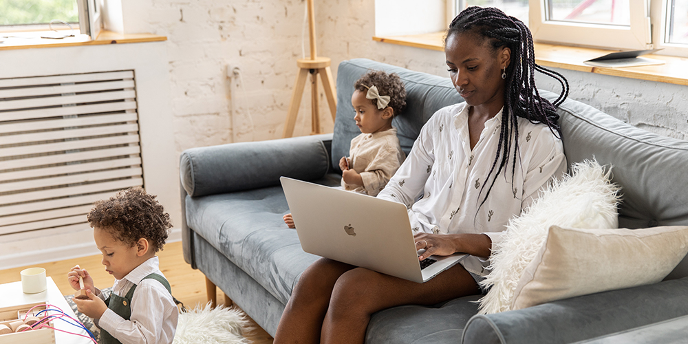 A working parent with two children playing near the couch while they update their career gaps profile.