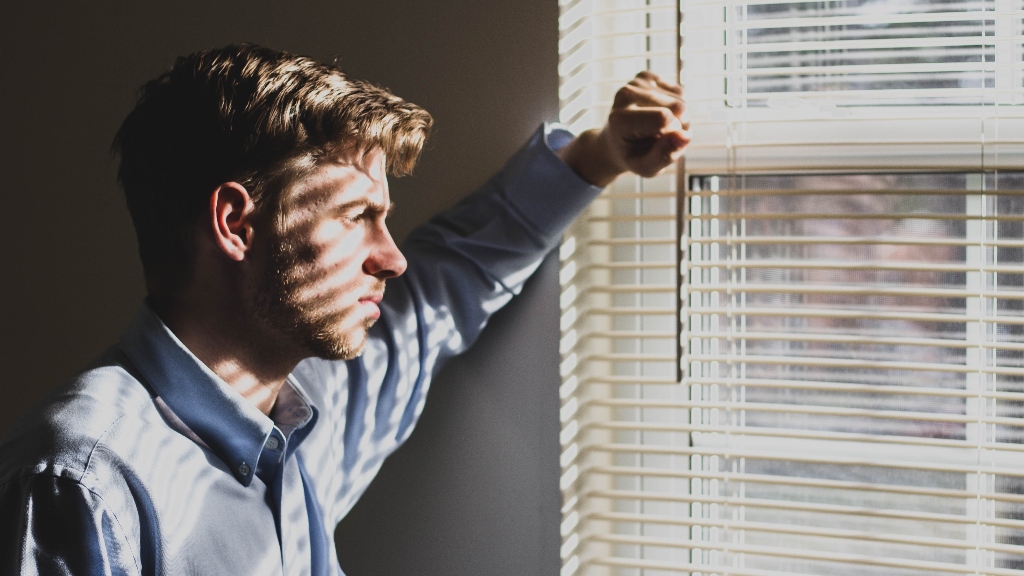 person looking out window representing job search desperation