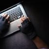 Hands with gloves on laptop representing hackers