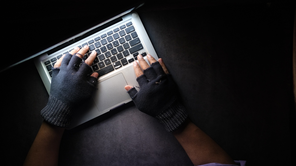 Hands with gloves on laptop representing hackers