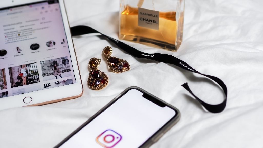 instagram on phone and ipad with earrings and perfume representing kim k crypto promotion