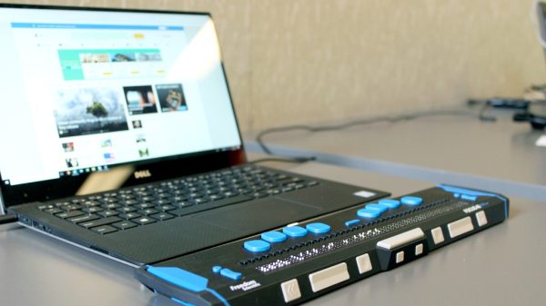 Accessibility keyboard with braille in front of laptop