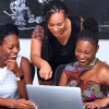 Three Black women are looking at a computer and chatting excitedly. Layoffs have led to a lot of innovation and new LLCs being formed.