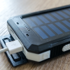 A charging device with solar panels, powered by lithium batteries, sits plugged in on a table.