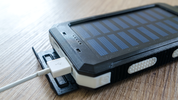 A charging device with solar panels, powered by lithium batteries, sits plugged in on a table.