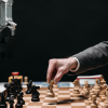 A man plays chess with an AI robot in the midst of layoffs.