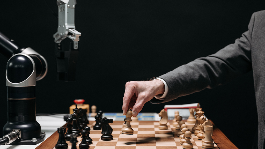 A man plays chess with an AI robot in the midst of layoffs.