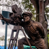 A bronze statue on Disney property depicting a director pointing past an old fashioned movie camera.
