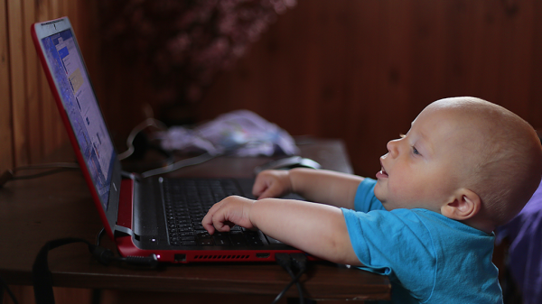 A baby typing at a laptop open to the former Twitter homepage.