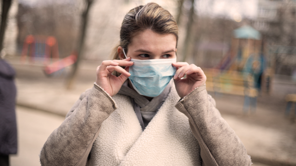 A woman in an autumn park wearing a face mask for protection after an NLRB order.
