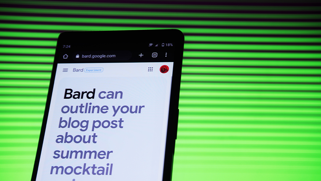 A smartphone open to Google Bard reading out "Bard can outline your blog post about summer mocktail" and then cuts off. The phone is held up against a green and black lined background.
