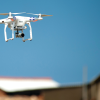 A drone flying over a set of houses. The camera is focused on the drones, while the neighborhood is blurred.