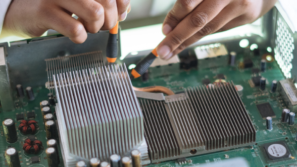 A close up of a computer chip with a pair of hands working on the various circuit boards.