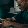 A Black man working on a computer microchip board, wearing safety goggles.