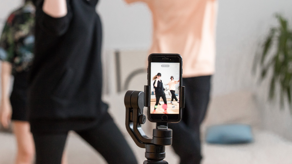 A phone in the foreground recording a pair of people recreating a Tiktok dance