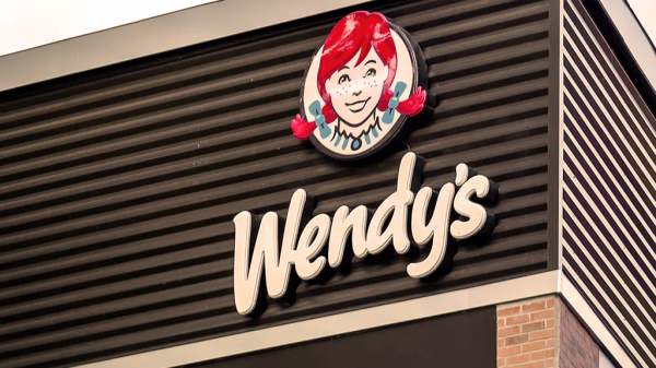 An outdoor sign of a Wendy's restaurant, focusing on the logo and top of the roof.