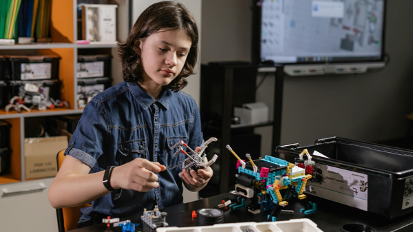 A young woman building with Legos in a classroom and creating a small vehicle.