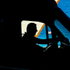 A silhouette of an amputee driving a truck, with a blue metal wall behind them.