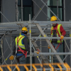 Two construction workers climbing on a set of rigging following OSHA guidelines for fall safety.