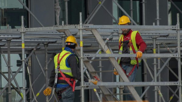 Two construction workers climbing on a set of rigging following OSHA guidelines for fall safety.
